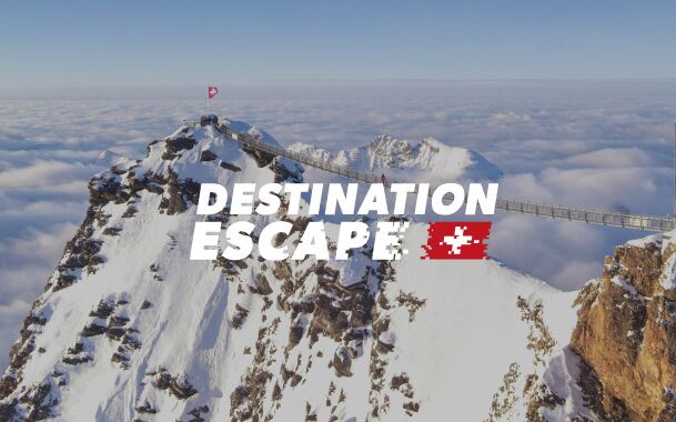 Schweizer Berge über einem Wolkenmeer und das Logo von Destination Escape