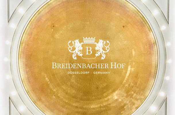 Photo of the golden domed ceiling of Breidenbacher Hof and the hotel logo